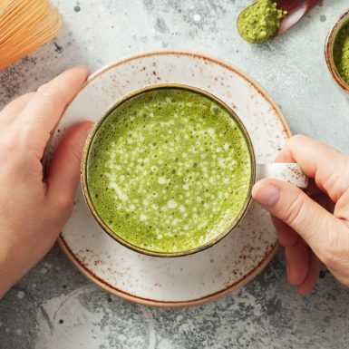 Cup of Matcha Green Tea in woman hands. Top view. flat lay.