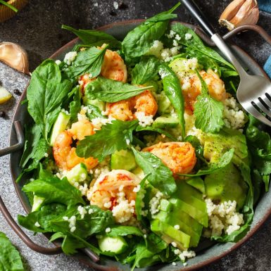 Healthy food. Dieting dinner. Couscous salad with arugula, avocado and grilled shrimps.